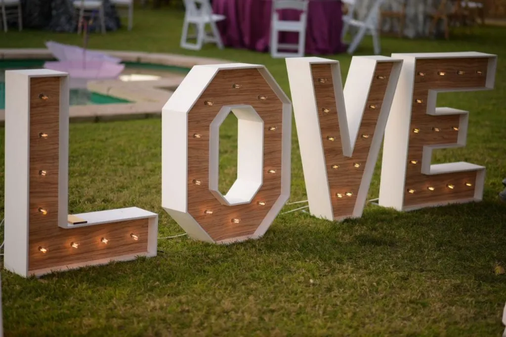 Letras LOVE con luz en un jardín