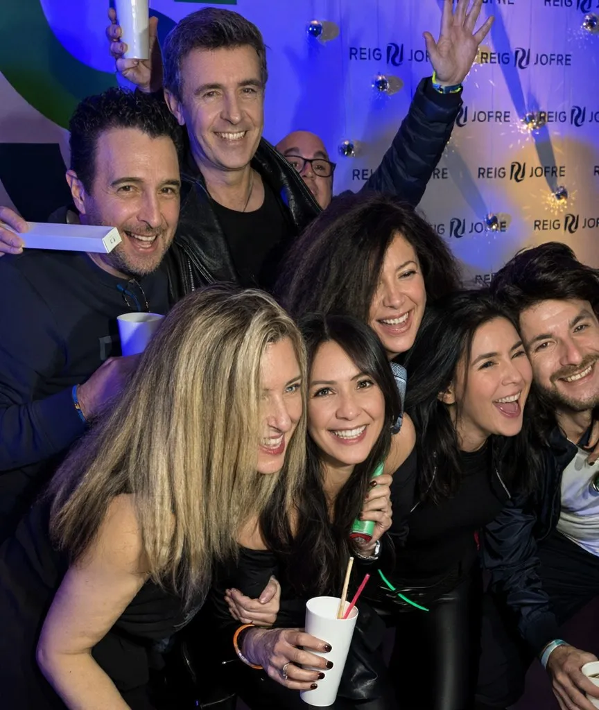 Grupo de amigos riendo en el fotomatón en una fiesta de noche