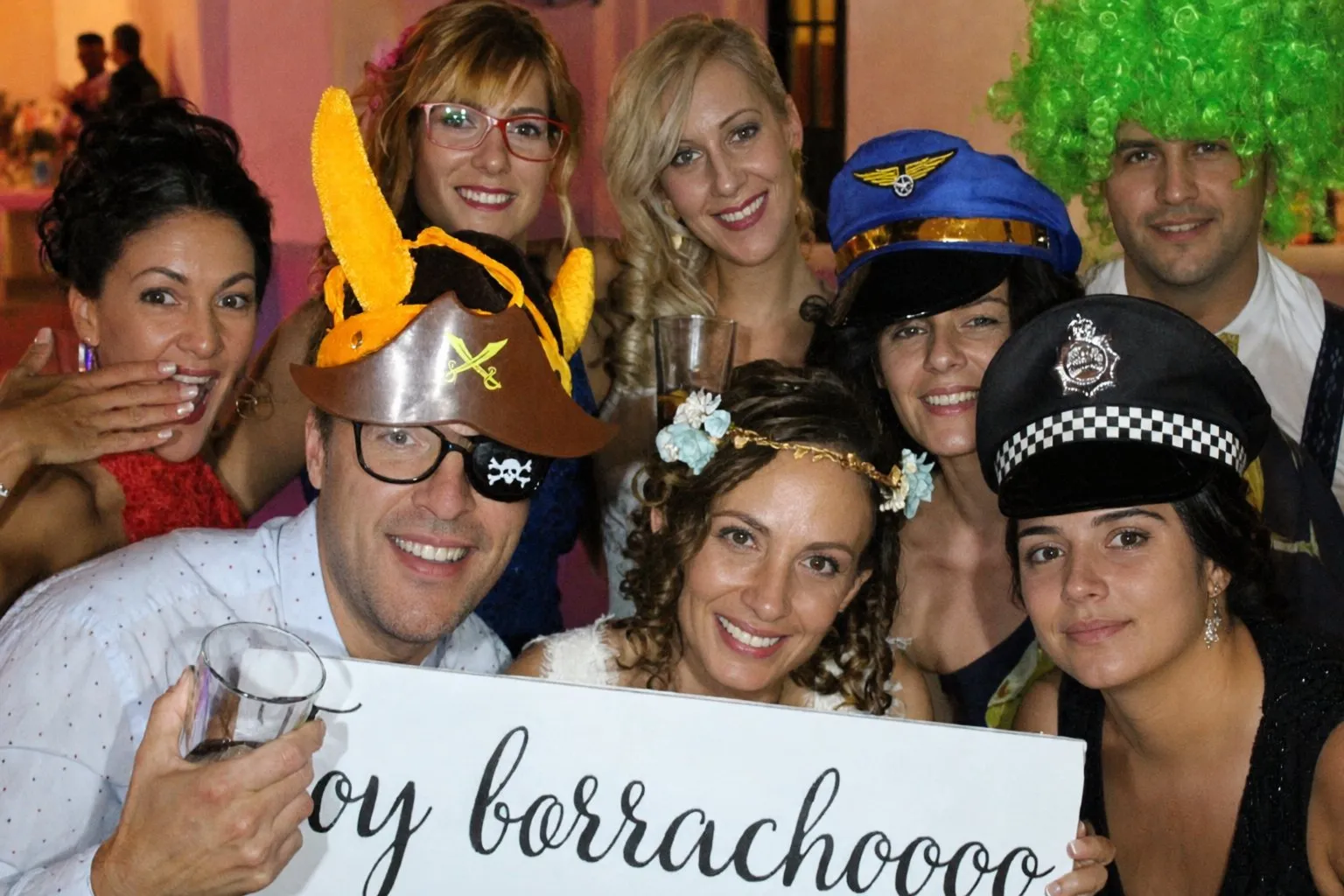 Invitados disfrazados con gorros y carteles divertidos