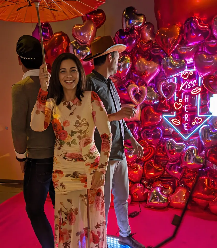 Invitada con sombrilla en la plataforma 360, delante de una pared de globos de corazones