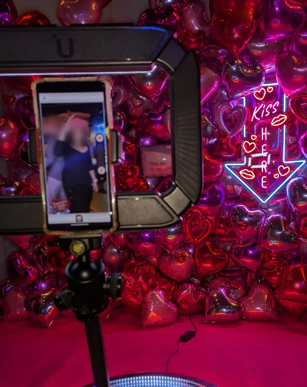 Phone recording on the 360 platform in front of a wall of heart balloons