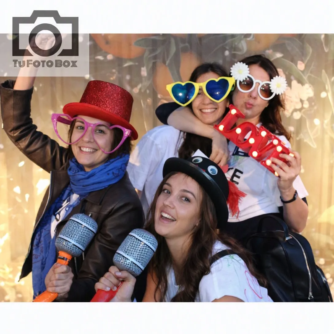Amigas con sombreros, gafas y micrófonos de atrezzo