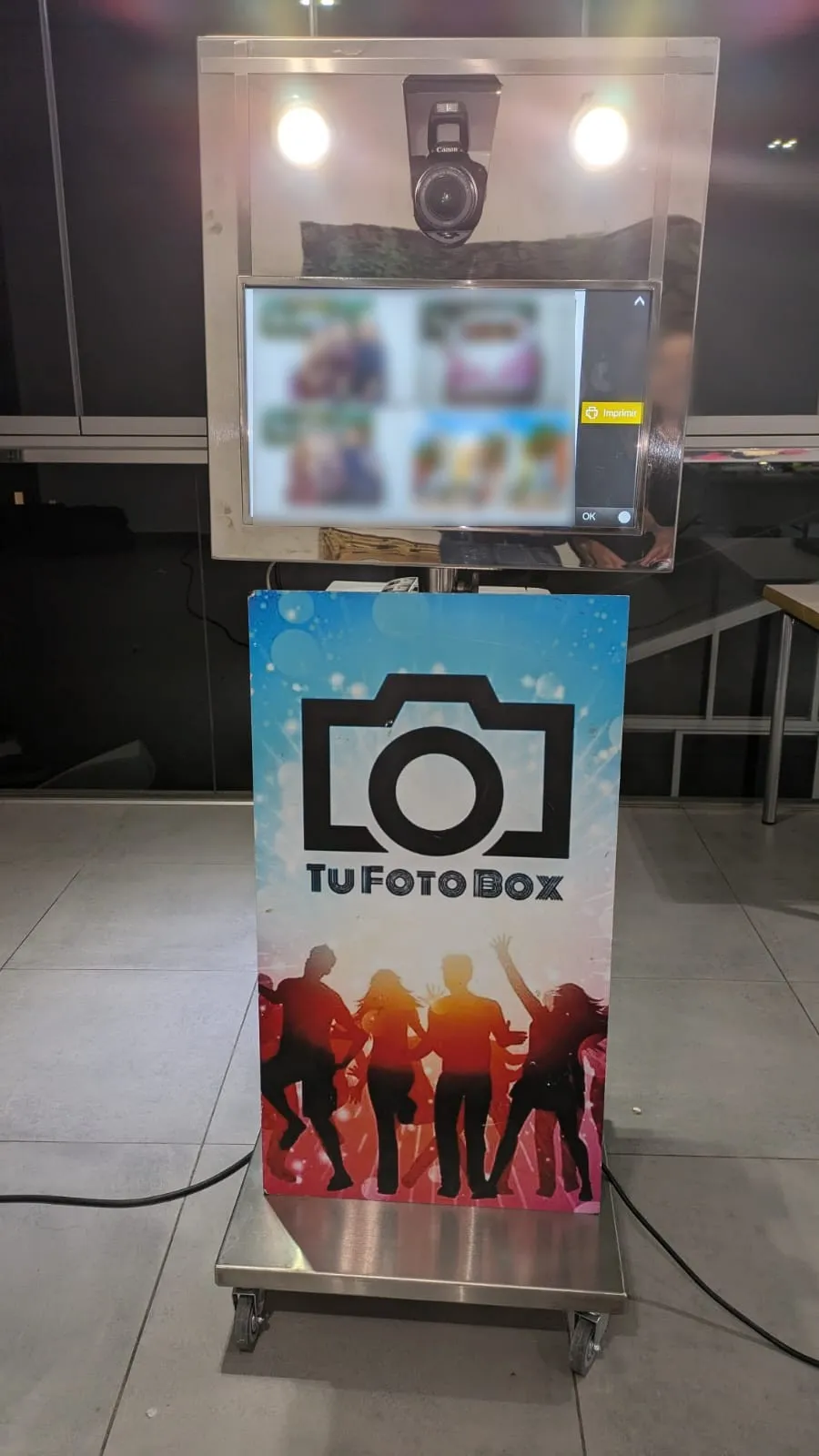 Silver steel photo booth with a DSLR camera, two flashes and a touch screen, set up at an event